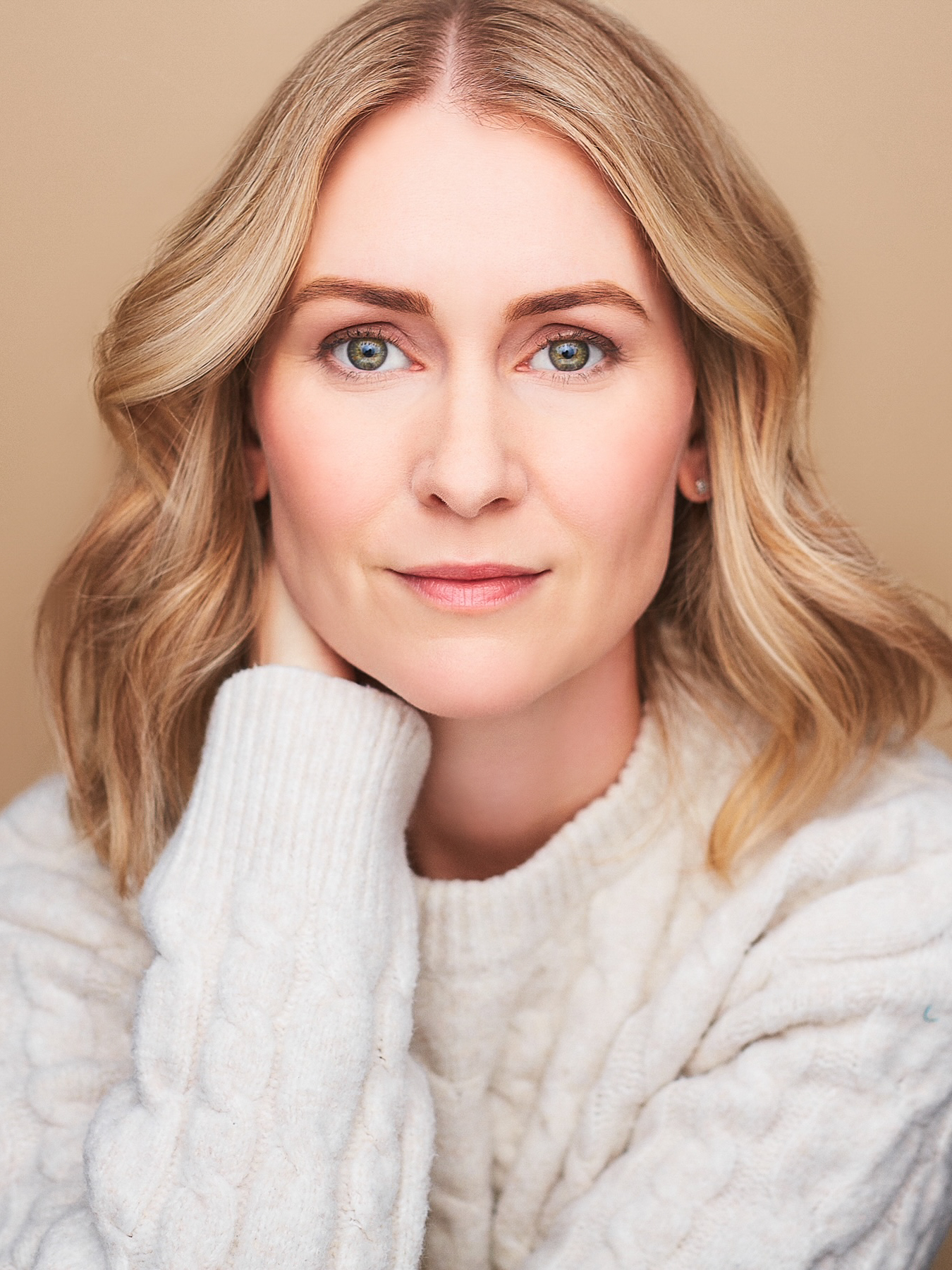Botts Heather – The REV Theatre Co. | Broadway in the Finger Lakes Close-up portrait of a woman with blue-green eyes and blonde hair, wearing a cream knit sweater and looking at the camera.